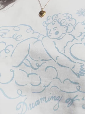 Charlotte Mills - Angel - White t-shirt with blue cherub graphic design and text that reads "dreaming of I 'do'"